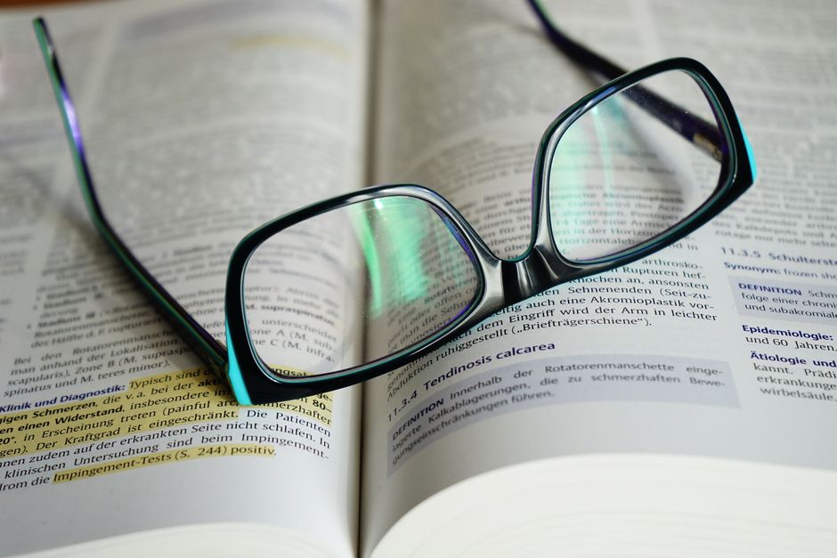Naočale za čitanje na otvorenoj knjizi, simbol znanja i mentorstva
