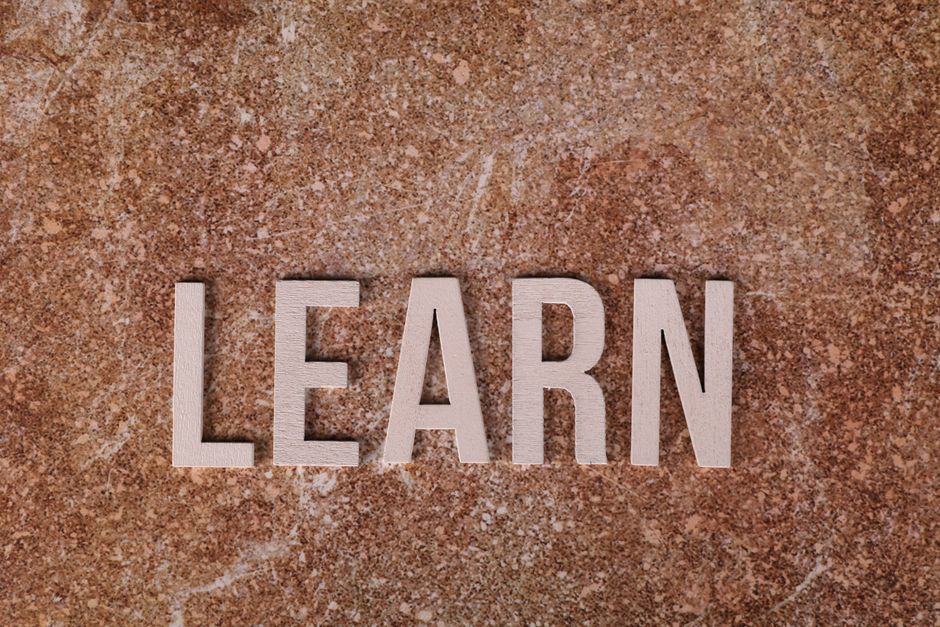 Wooden letters spelling 'Learn' na mramornoj podlozi, simbol učenja i rasta